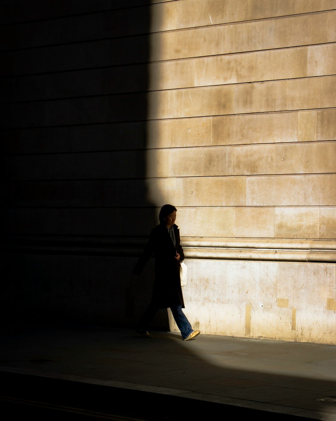 a person walking down a sidewalk next to a building